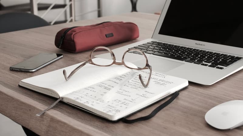 notebook, glasses and laptop on desk